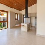 Sala e cozinha integradas com pé-direito em madeira da casa térrea no Condomínio Alto do Sion, Atibaia
