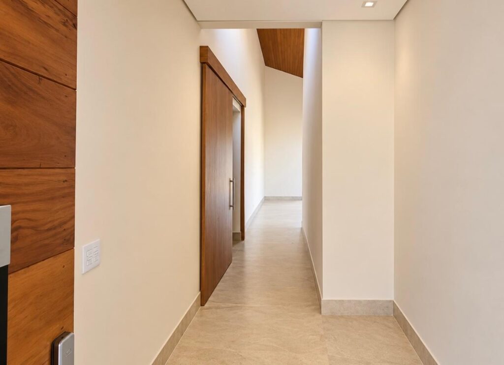 Corredor com porta pivotante da casa térrea no Condomínio Alto do Sion, Atibaia
